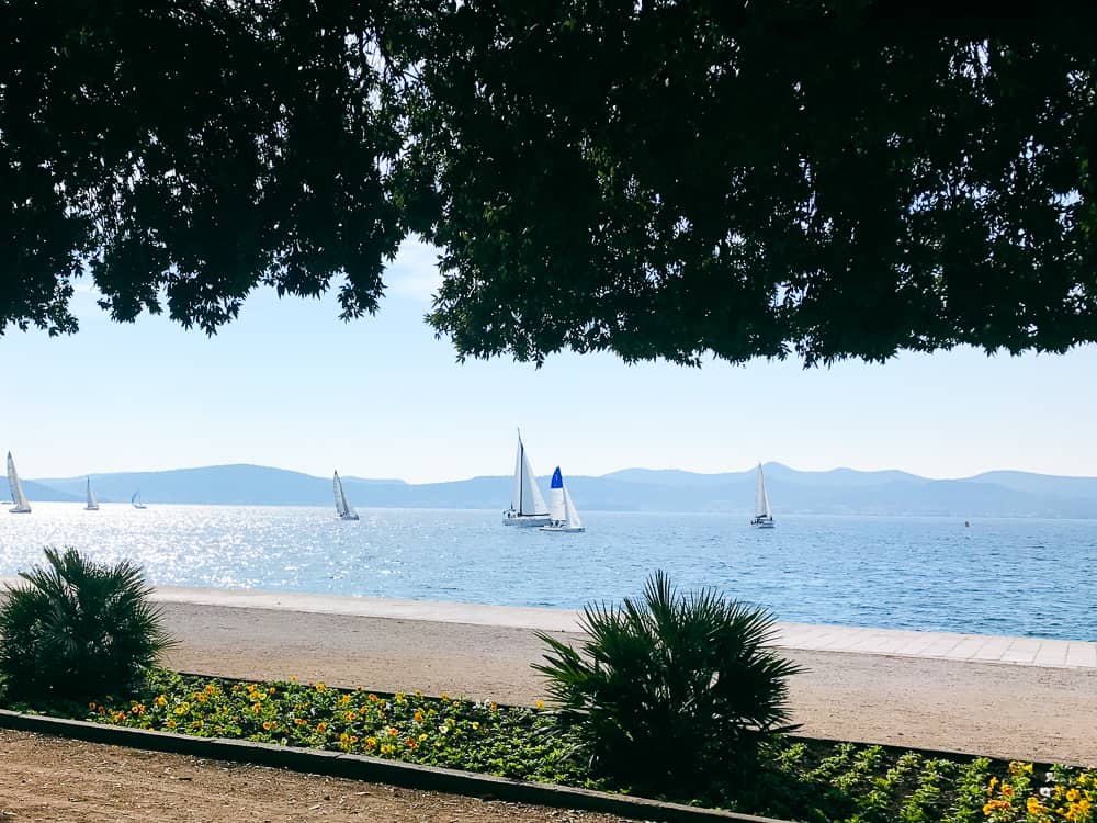 Sailboats on the blue Adriatic Sea, framed by the shaded waterfront in Zadar.