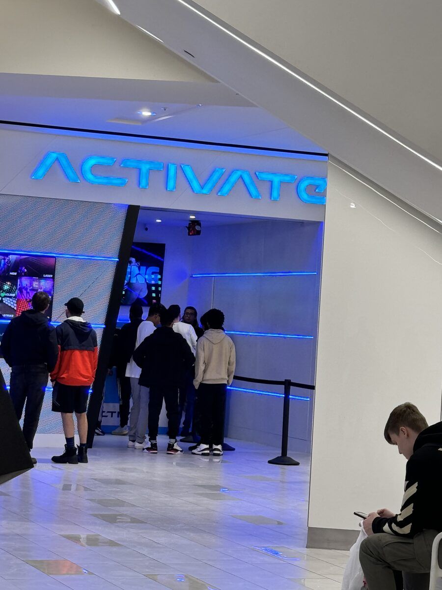 A queue of people outside the blue neon entrance to ACTIVATE