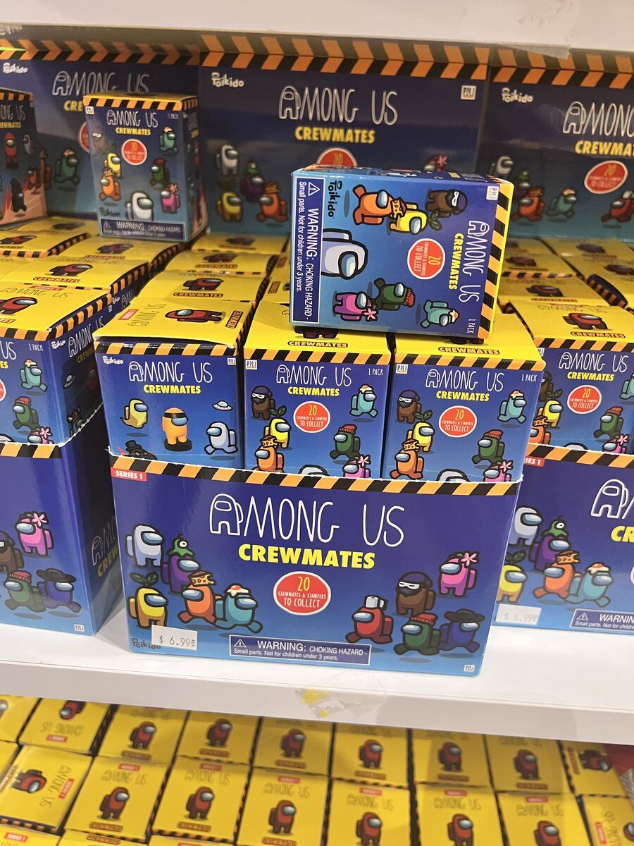 Stacked yellow and blue boxes of Among Us Crewmates toys on a shop display