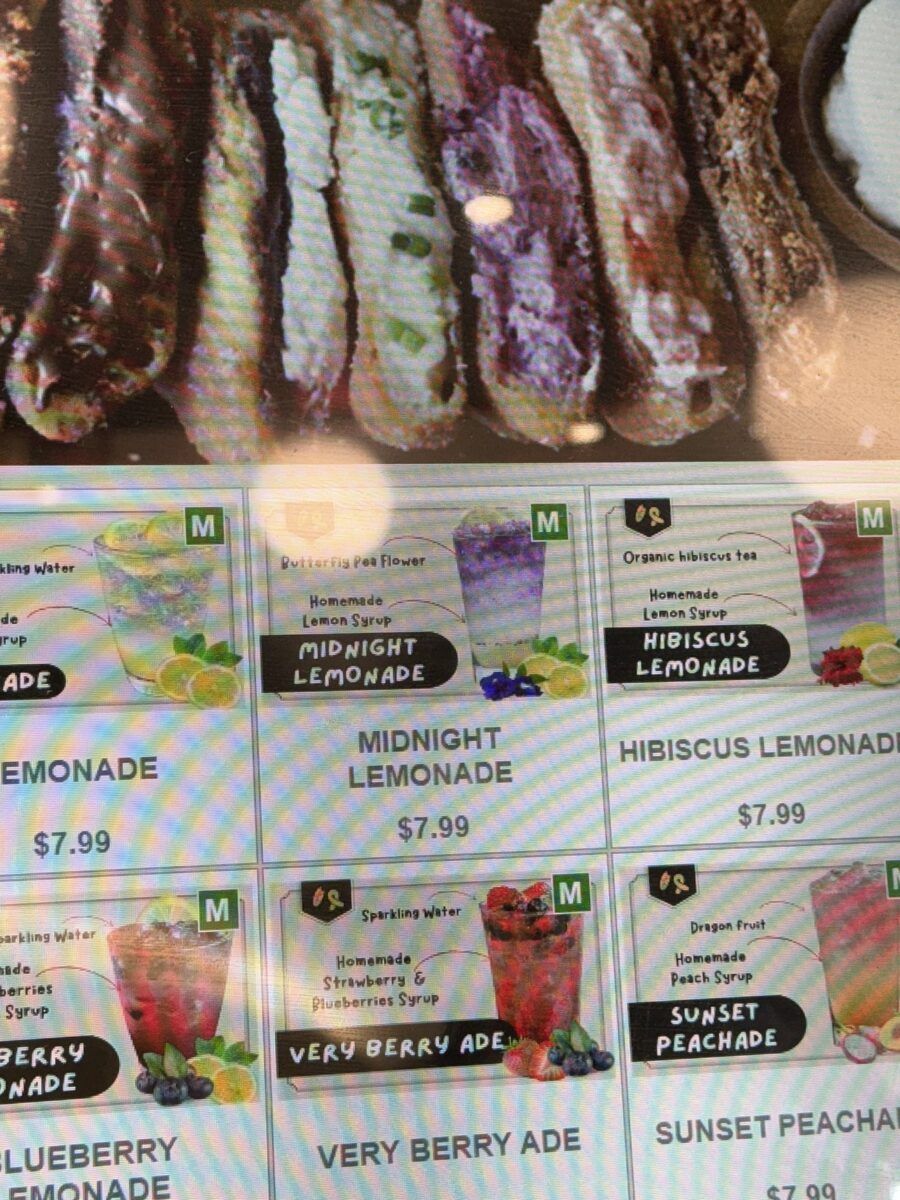 A drinks menu board listing Midnight Lemonade at 7.99 dollars, made with butterfly pea flower and homemade lemon syrup