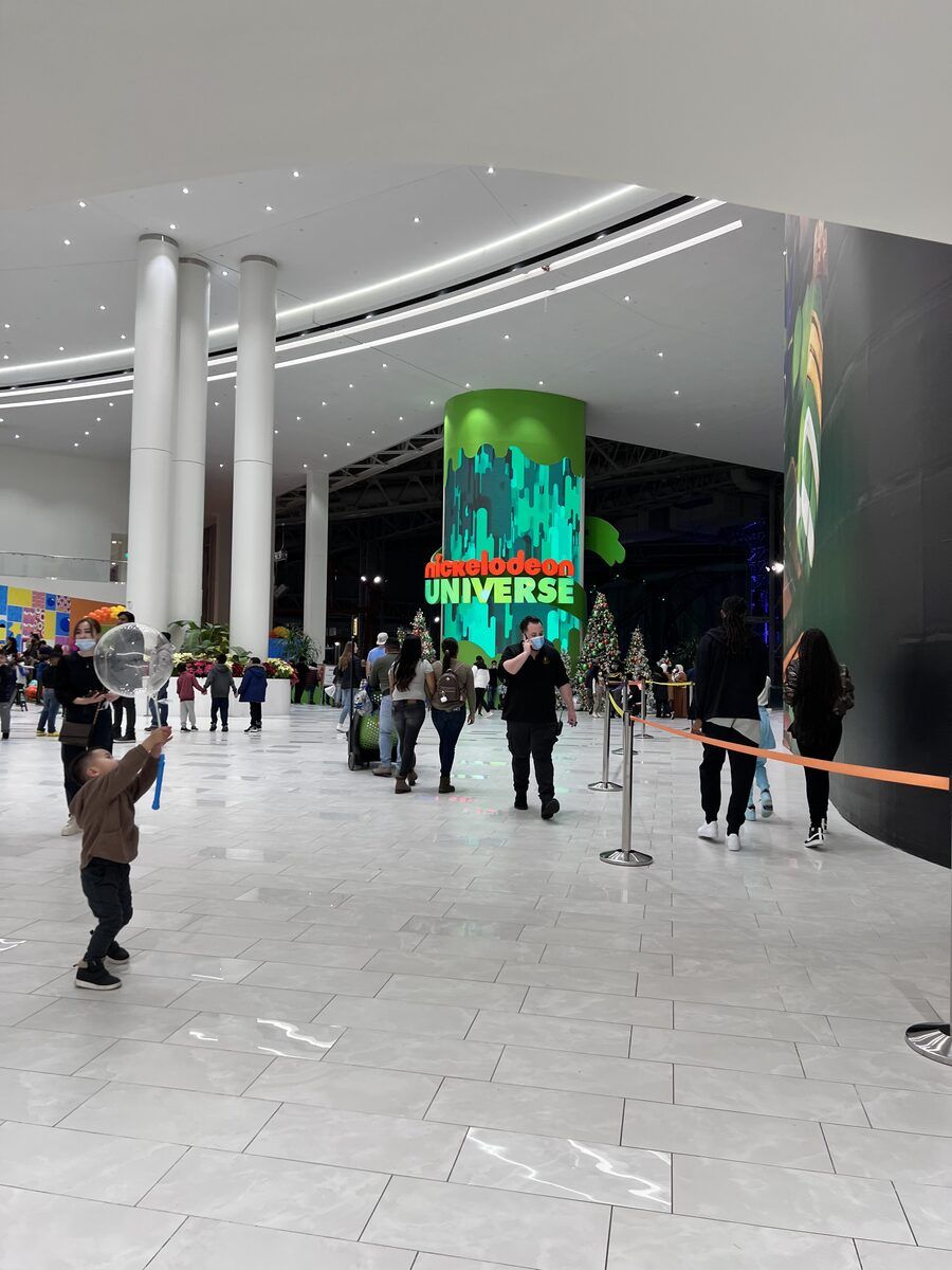 The lit entrance to the Nickelodeon Universe indoor theme park seen across a mall concourse