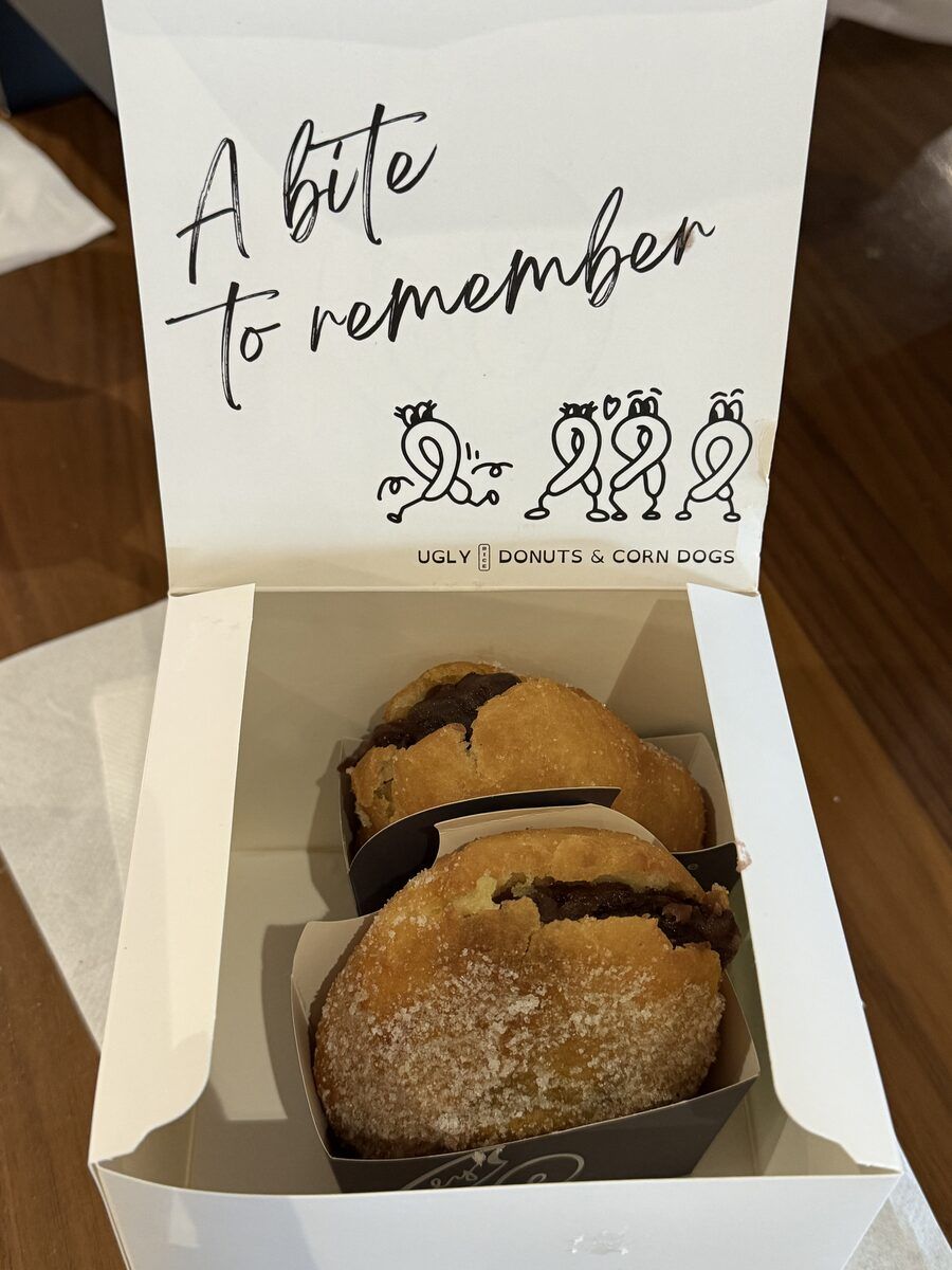 An open box of two donuts with A bite to remember printed inside the lid