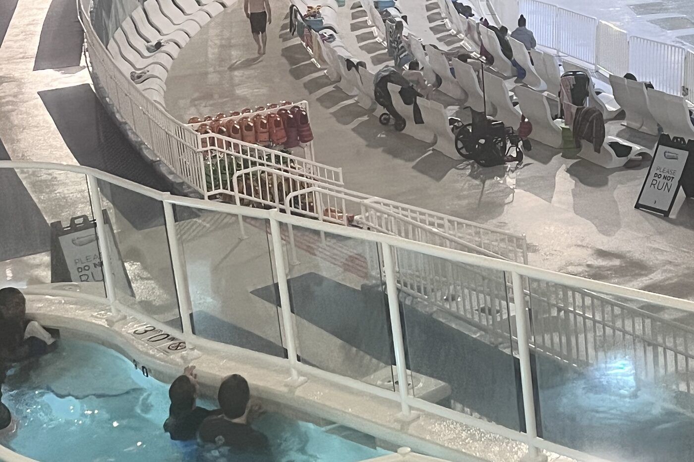 An indoor water park wave pool and rows of empty loungers seen from a walkway above