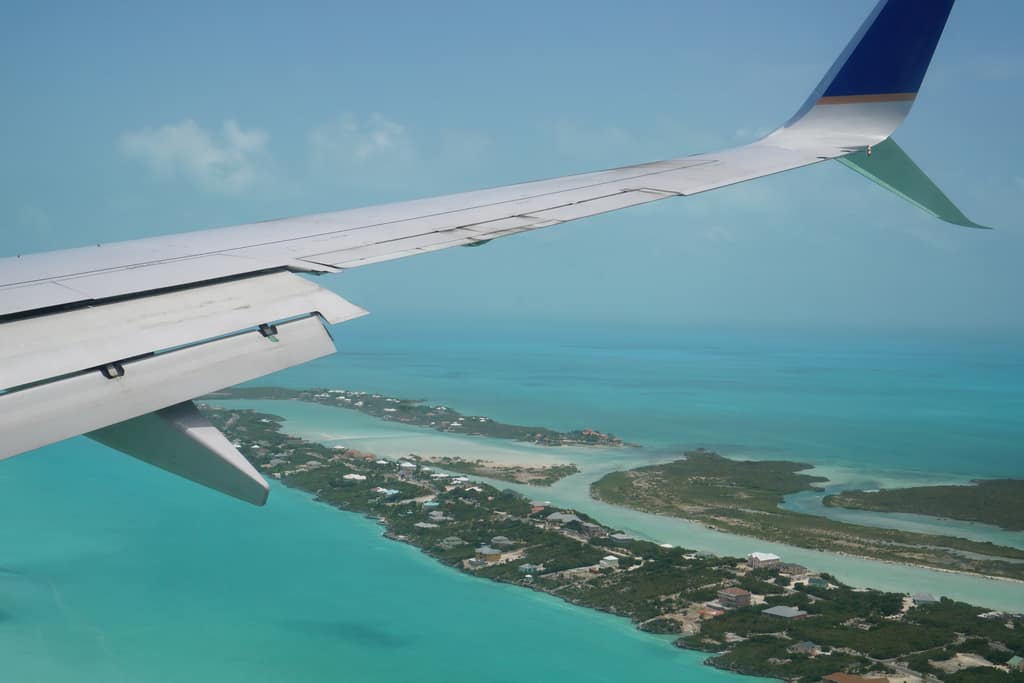 The turquoise shallows and reef line of Providenciales seen from an aeroplane wing
