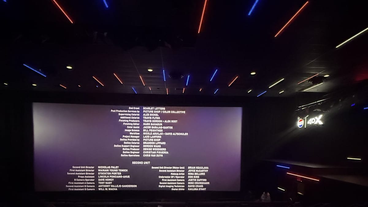 The dark 4DX auditorium at Regal Times Square with coloured light bars on the ceiling and the end credits on the screen