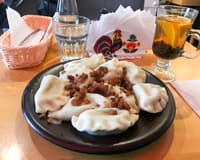 A black plate of pierogi topped with fried onion in a Warsaw restaurant