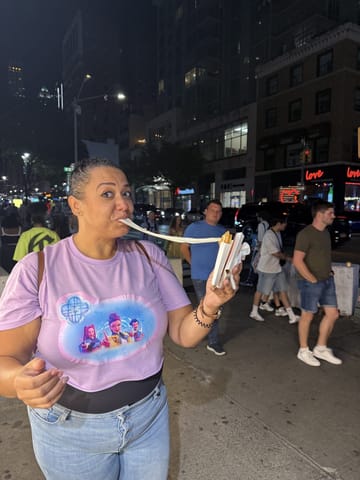 Carolyn on a Koreatown sidewalk at night stretching a long string of mozzarella from her gold coin bread
