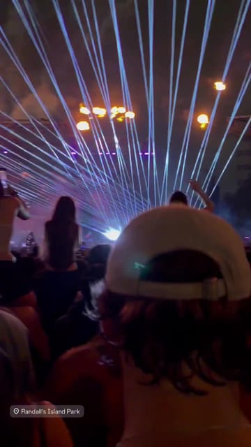 Pale blue lasers fanning out over the crowd while flames burst from the top of the stage