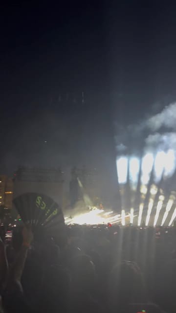 White light beams fanning up from the main stage through smoke after dark