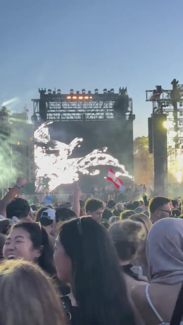 The main stage in the last of the daylight, white visuals swirling on the screen above a packed crowd