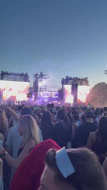 The main stage at dusk with three glowing screens, purple haze and a blue sky