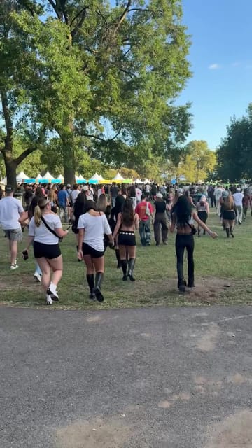 Festival-goers streaming across the grass toward the tents in the late-afternoon sun