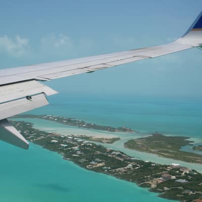 The turquoise shallows and reef line of Providenciales seen from an aeroplane wing
