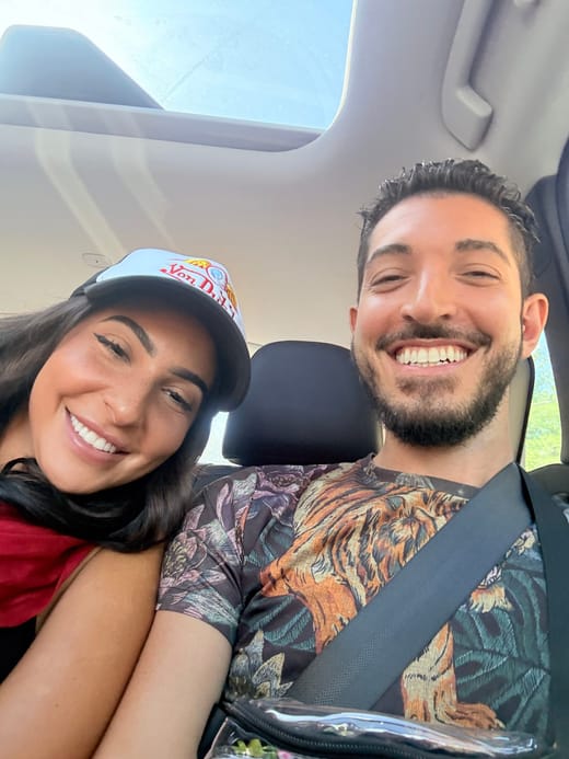 Rocky and his sister Tiffany smiling in the back seat of a car under a sunroof, Tiffany in a trucker hat