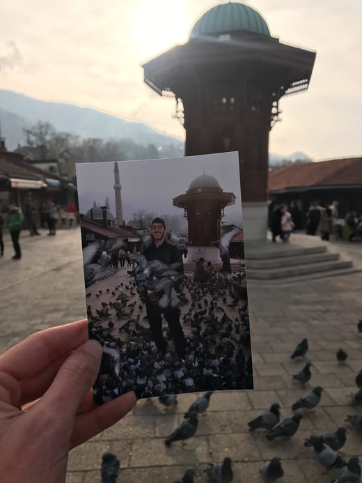 A printed photograph of Pigeon Square held up in front of the real square