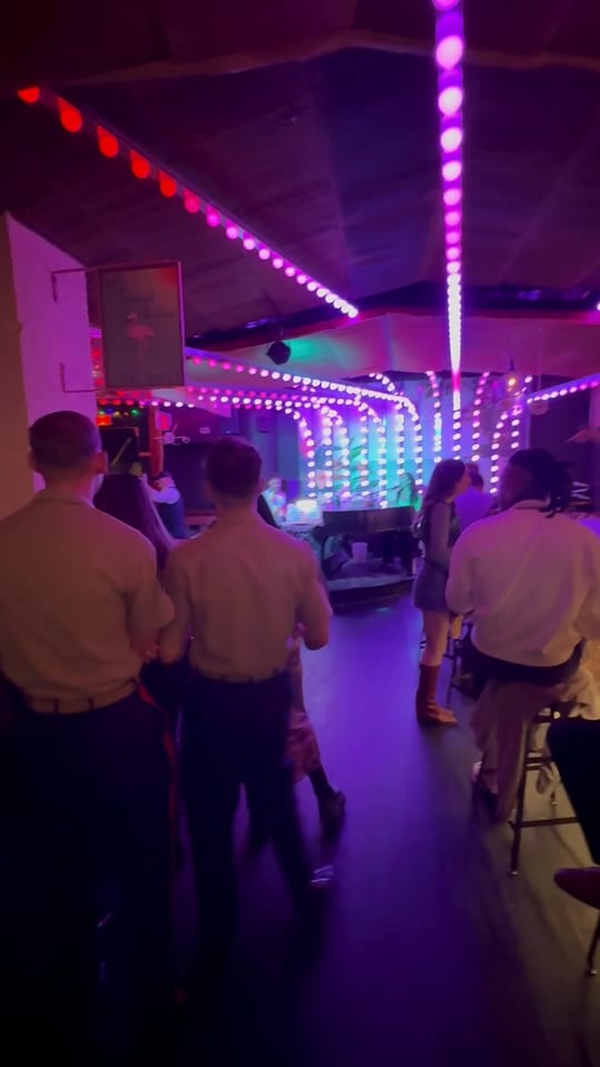 A group of Marines in khaki uniforms walking into The Friki Tiki as the room shouts its welcome