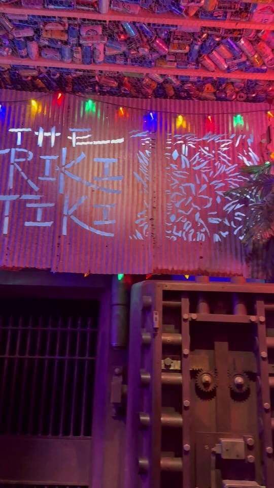 The Friki Tiki bar sign and vault door glowing under red and pink neon