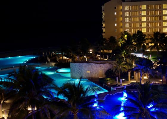 The resort pools glowing blue at night from a balcony in Cancun