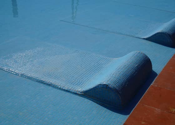 A tiled bed built into the shallow end of the pool, half submerged in water