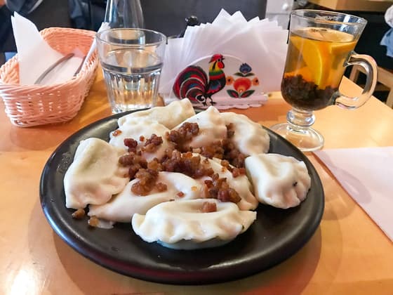 A black plate of pierogi topped with fried onion in a Warsaw restaurant