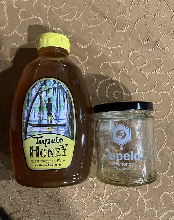 An empty Adagio tupelo jar next to a 2 lb squeeze bottle of Sleeping Bear Farms tupelo honey
