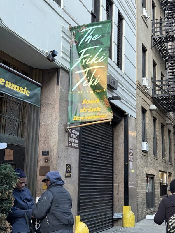 A green hanging banner for The Friki Tiki reading live music, food, drink over its entrance on West 44th Street