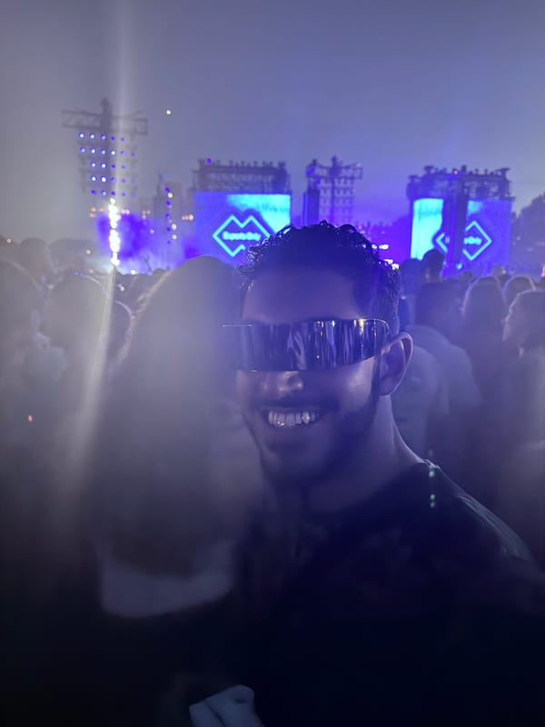 Rocky in wraparound mirrored visor glasses in the crowd, blue stage screens showing the Experts Only diamond logo behind him