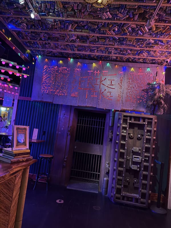 Inside The Friki Tiki, a round steel bank vault door beside the bar under strings of coloured lights