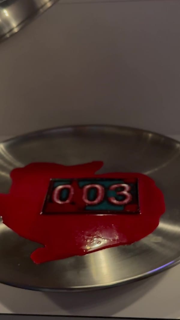 A red squid-shaped tag reading 003 on a silver plate