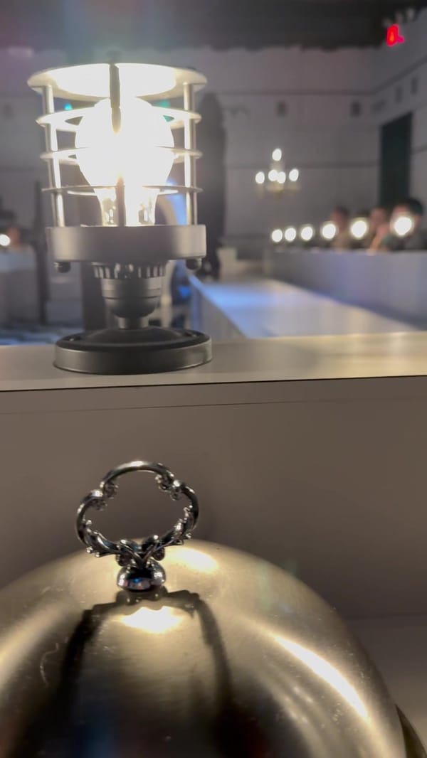 A silver cloche on a pedestal in the finale room, lit from above