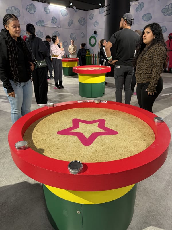 A round red marble station with a pink star in the sand, players standing around it