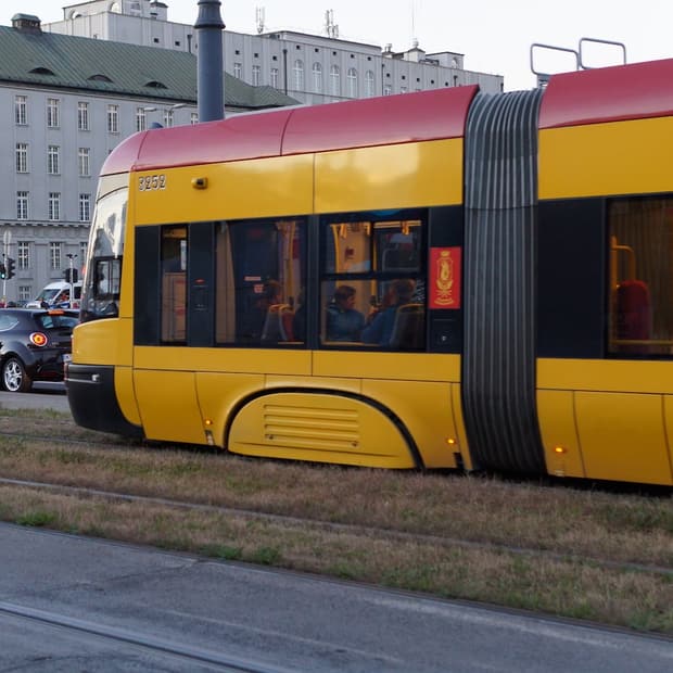 A yellow Warsaw tram on a city street