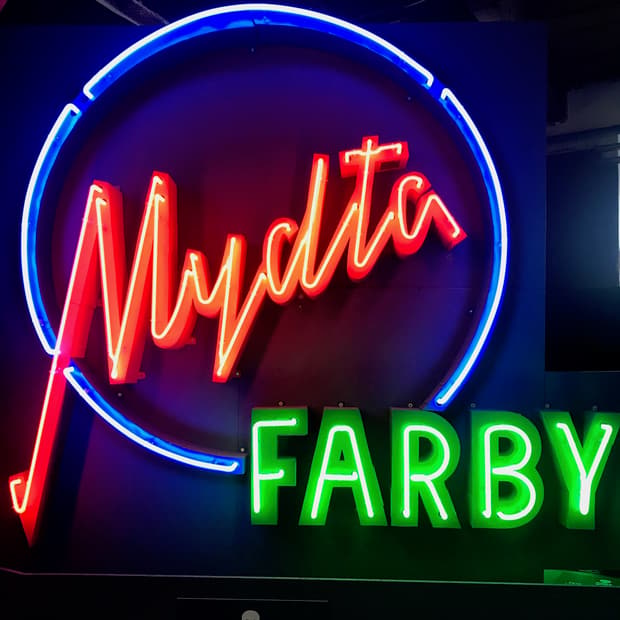 A tall blue and red neon sign reading Mydla i Farby