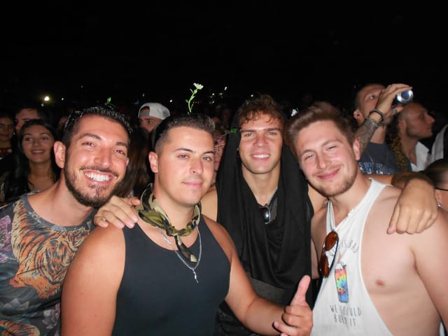 Rocky, Vinny, Nick and Zach with their arms around each other in the crowd at night, all smiling, a couple of sprout clips poking up from their heads