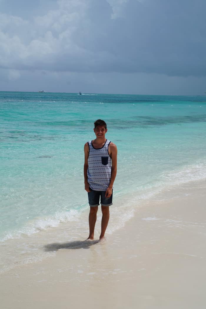 Standing barefoot on the white sand at the edge of the water