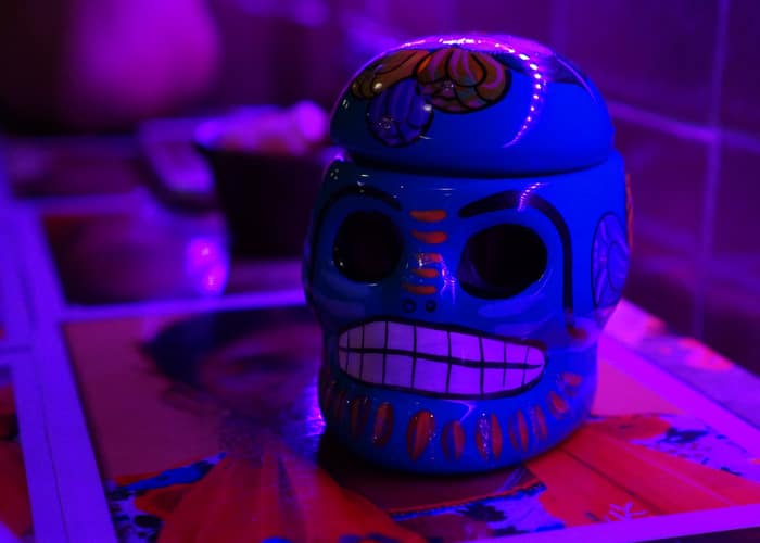 The blue sculpted calavera Rocky brought home from Cancun, lit from the side