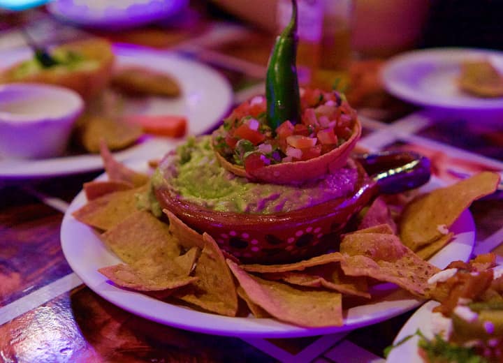 Freshly made guacamole with tortilla chips, salsa and a whole green chilli on top
