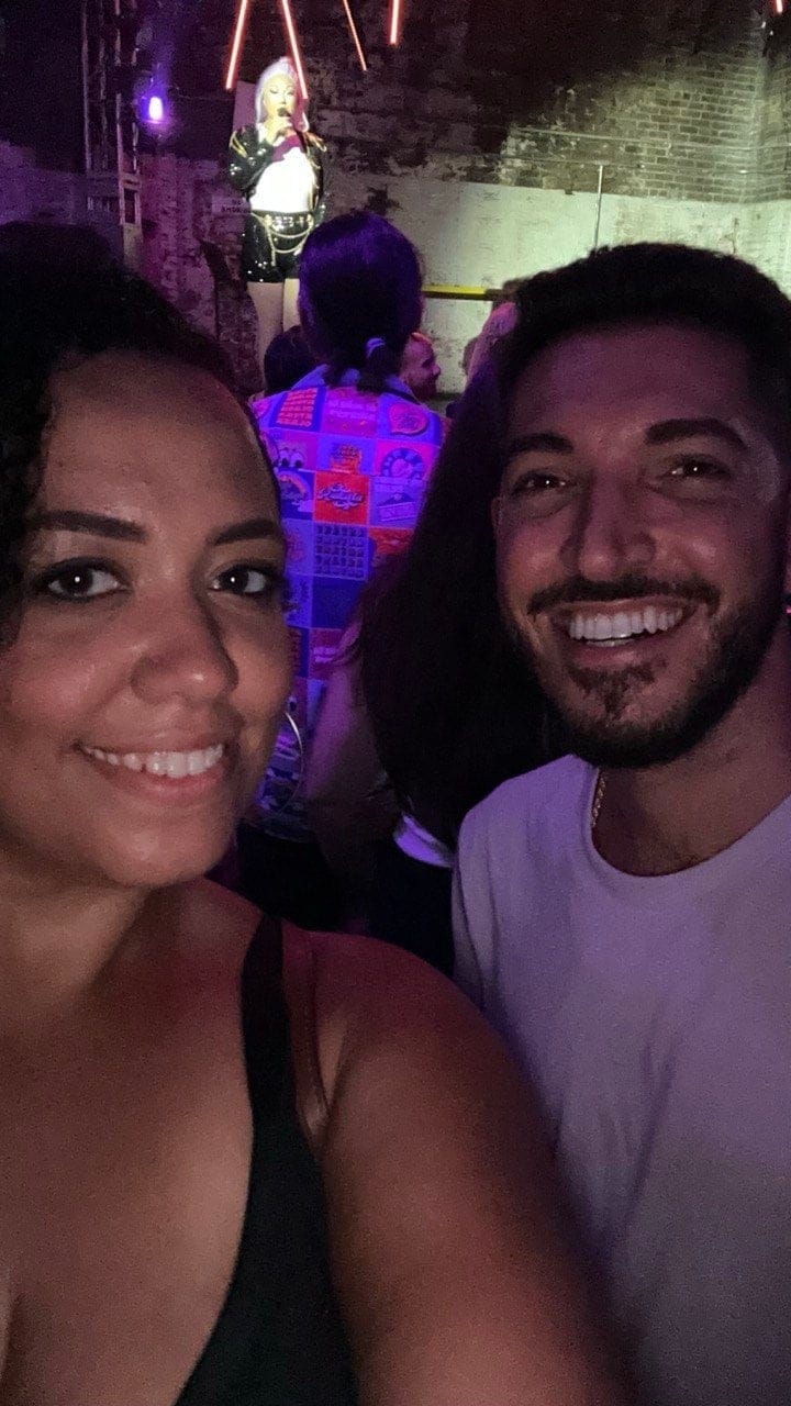 Rocky and his friend Carolyn smiling in a selfie at 3 Dollar Bill, a performer on stage behind them