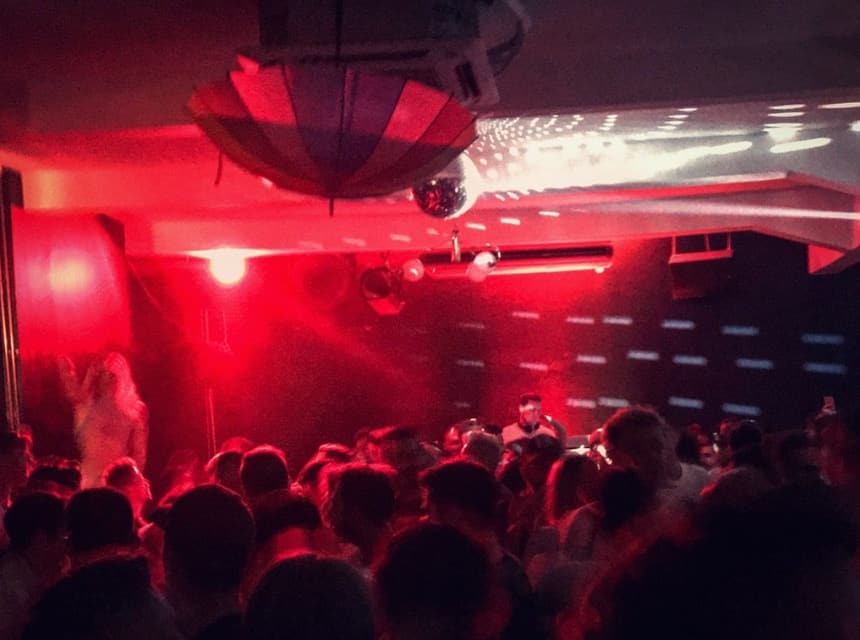 Red lights over a packed nightclub dance floor in Warsaw