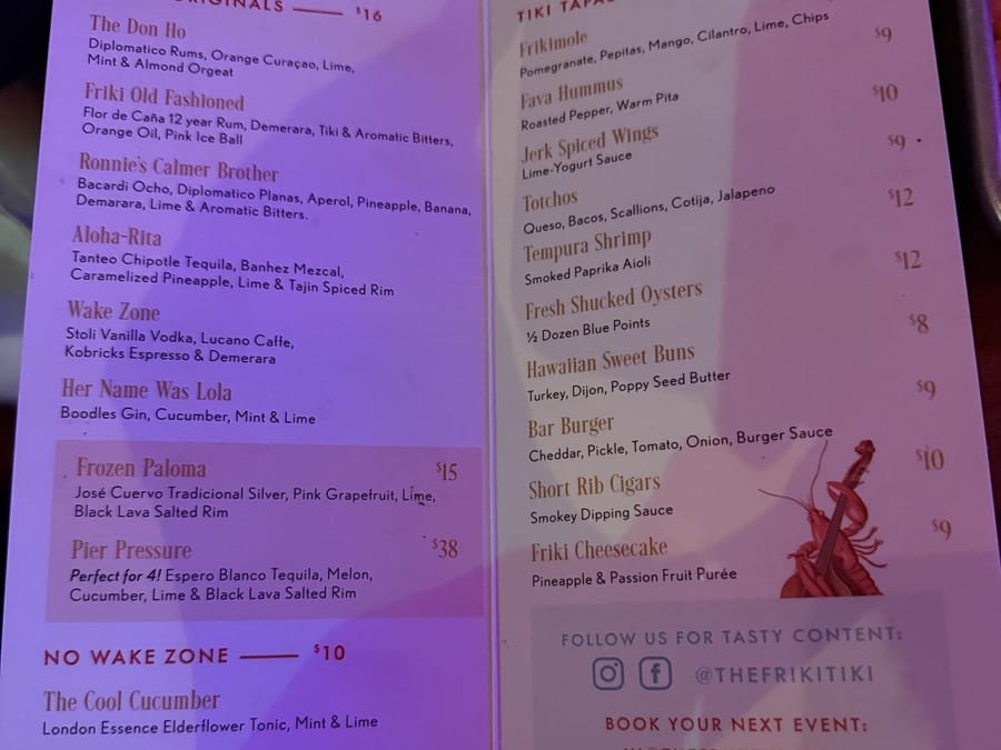 The Friki Tiki menu open to its Bottoms Up house cocktails page and its Big Mouthfuls tiki tapas page