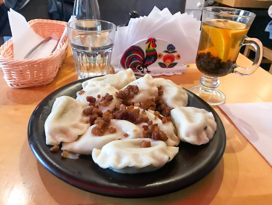 A black plate of pierogi topped with fried onion in a Warsaw restaurant
